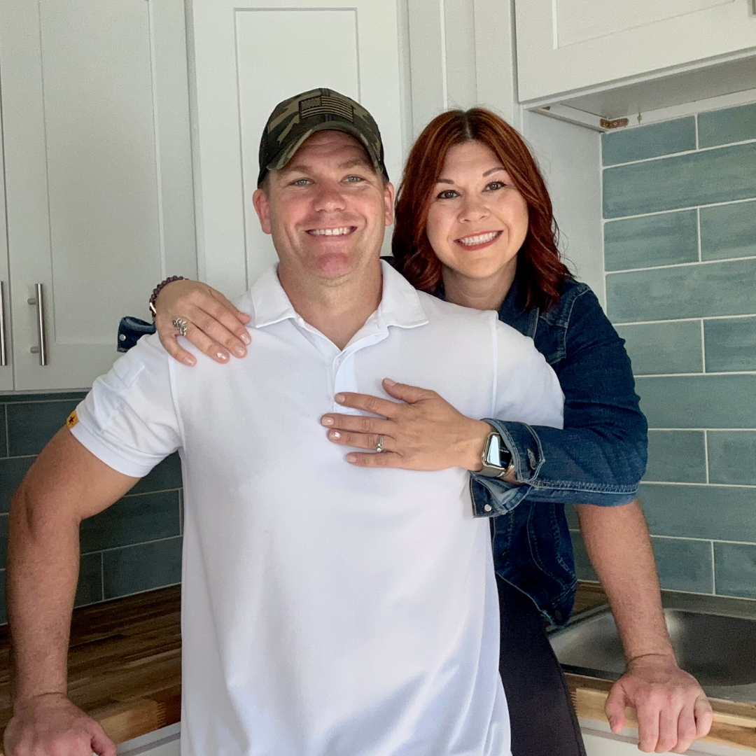 Meet the Heart Behind American Hero Properties We Buy Houses in Florida Smiling couple, owners of American Hero Properties, standing together in a modern kitchen, showing warmth and approachability.